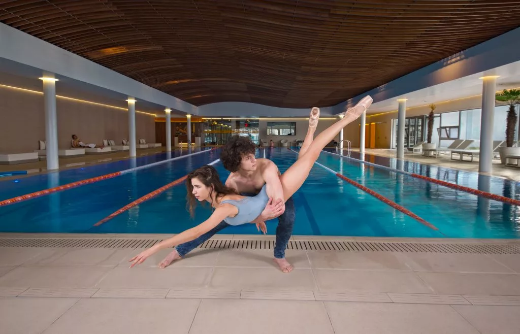 Doi dansatori sărind lângă piscina interioară a clubului Pescariu Sports & SPA