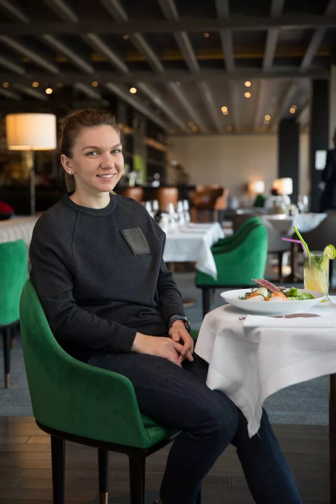 Simona Halep așezată la o masă din restaurantul clubului Stejarii, ședință foto pentru coperta revistei Stejarii