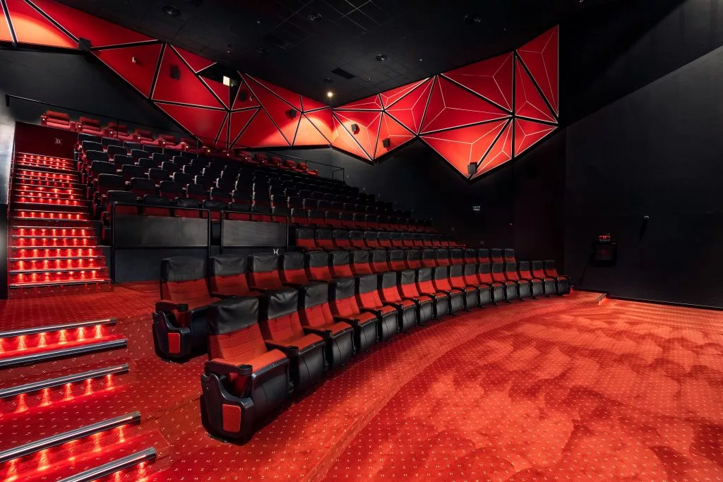 Sală de cinema Cineplex cu fotolii roșii și panouri geometrice pe pereți