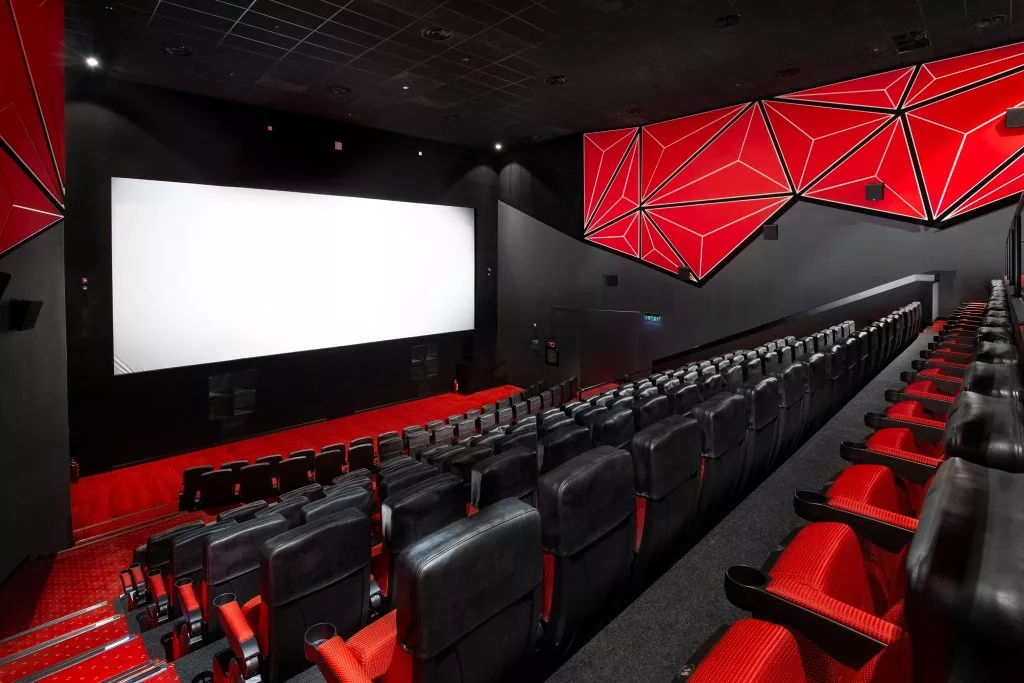 Sala Cineplex cu ecranul luminat și rândurile de fotolii