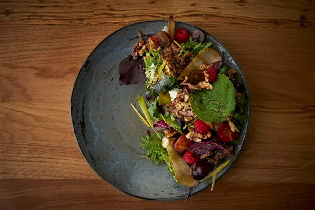 Salată cu verdețuri și fructe într-o farfurie ceramică, restaurant Melt