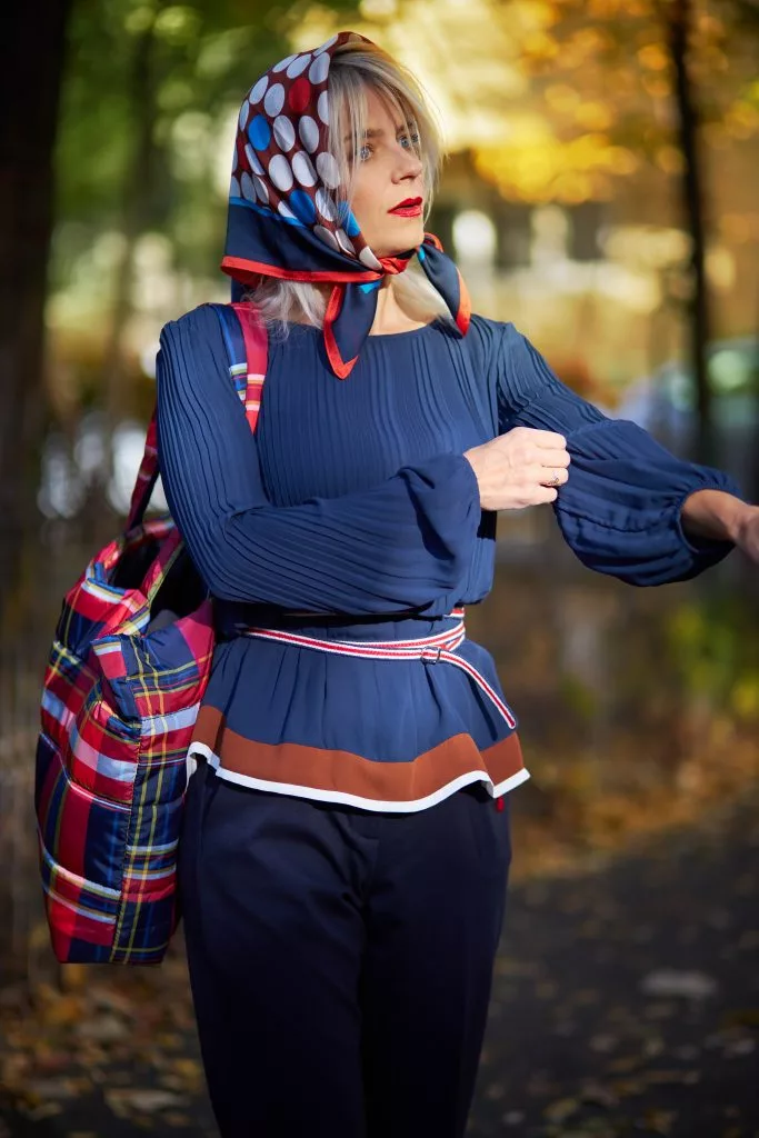 Model cu batic pe cap și bluză bleumarin, într-un parc de toamnă — campanie s.Oliver