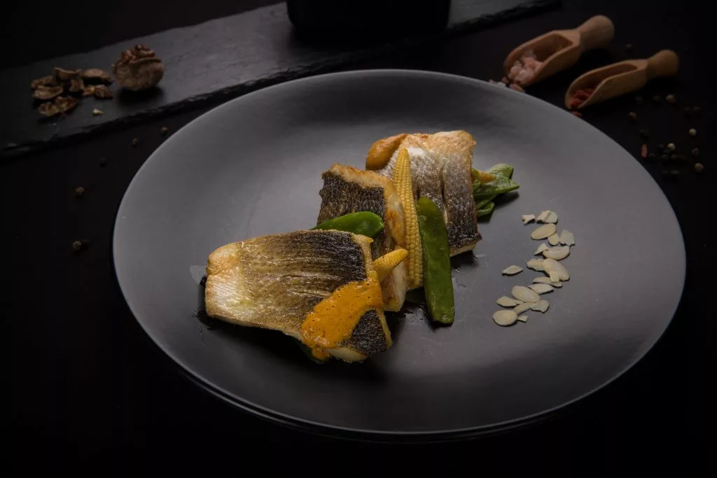 File de pește cu garnitură de legume, farfurie neagră — The Gallery