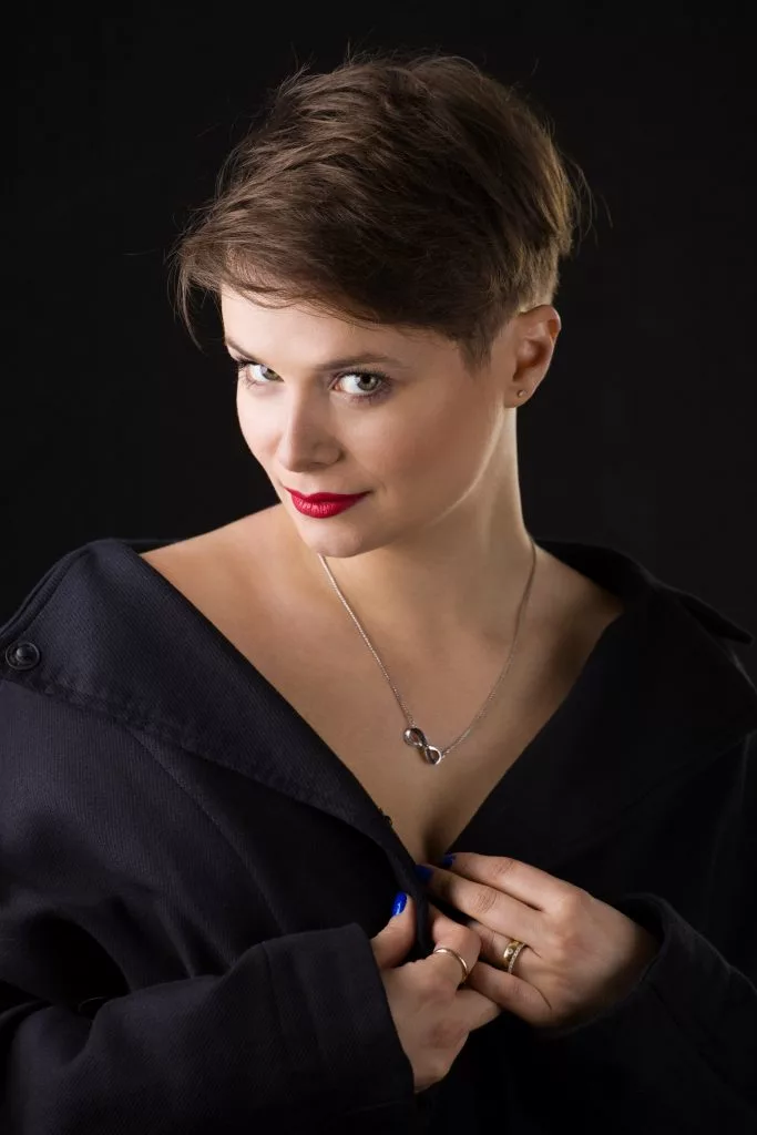 Diana Cavallioti în sacou negru, portret pe fundal întunecat