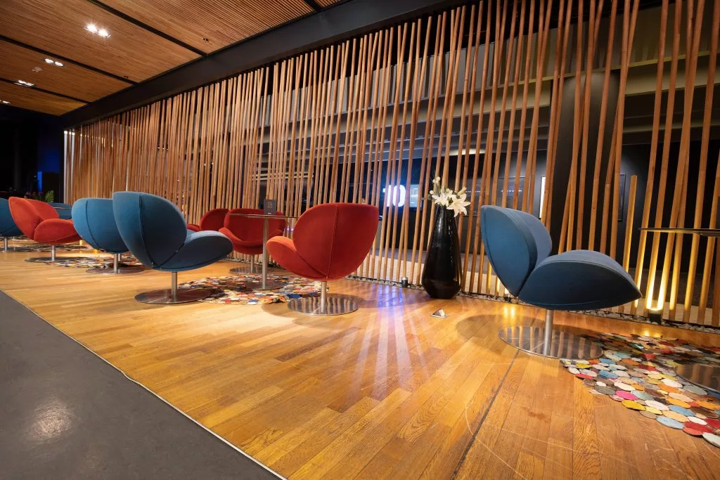 Lounge cu fotolii albastre și roșii în fața peretelui de lamele de lemn, Băneasa VIP Studio