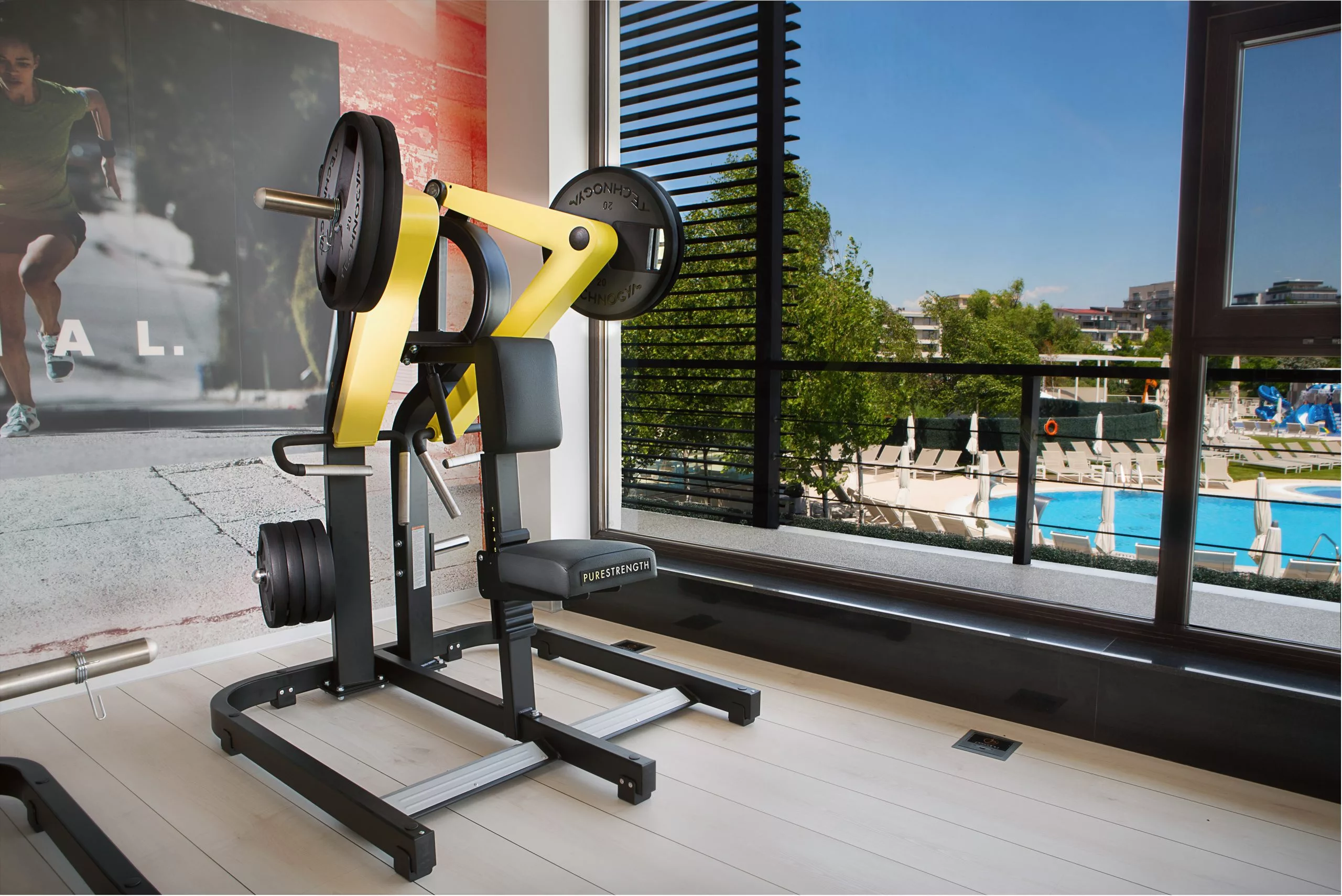 Aparat de forță cu discuri lângă fereastra spre piscină, Pescariu Sports & SPA