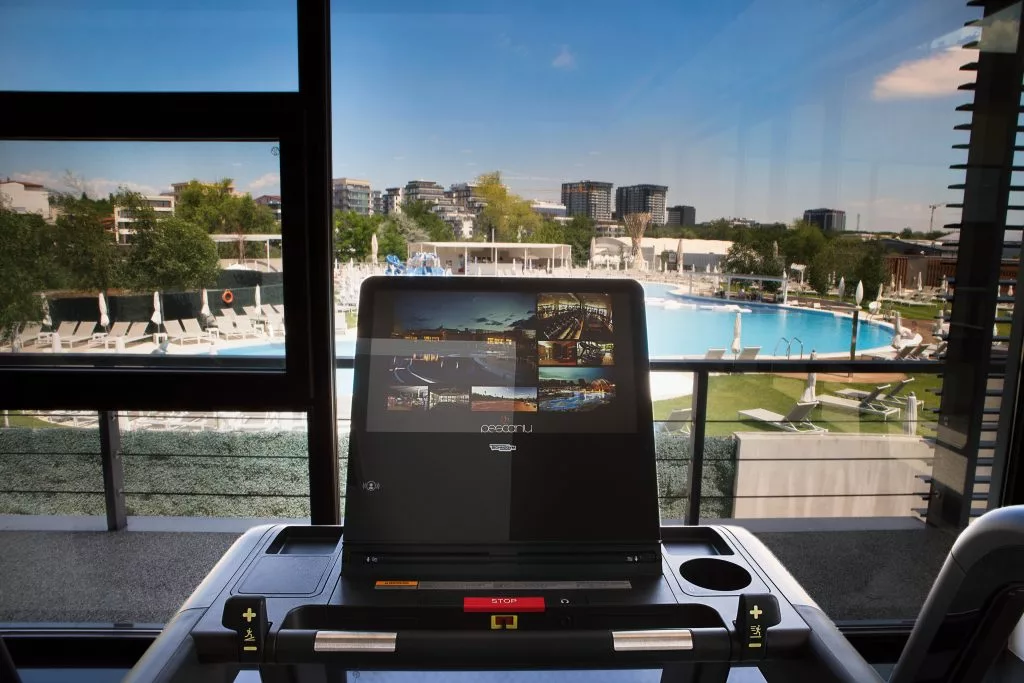 Bandă de alergat cu vedere spre piscina exterioară, sala de fitness Pescariu Sports & SPA