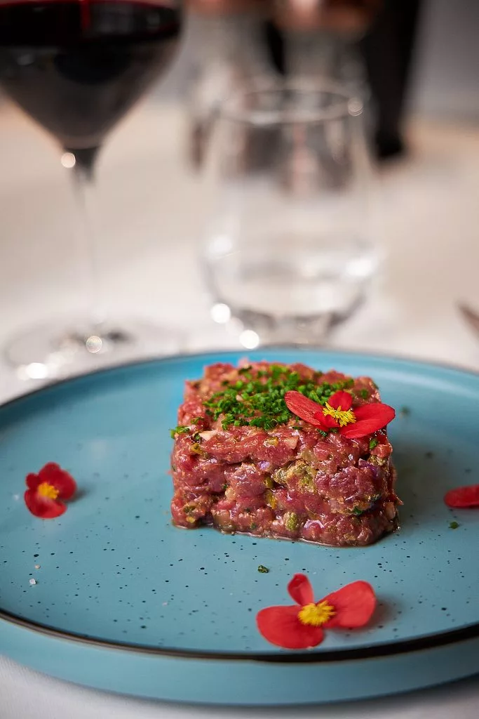 Tartar de vită cu flori comestibile, servit în farfurie bleu — Restaurant Stejarii