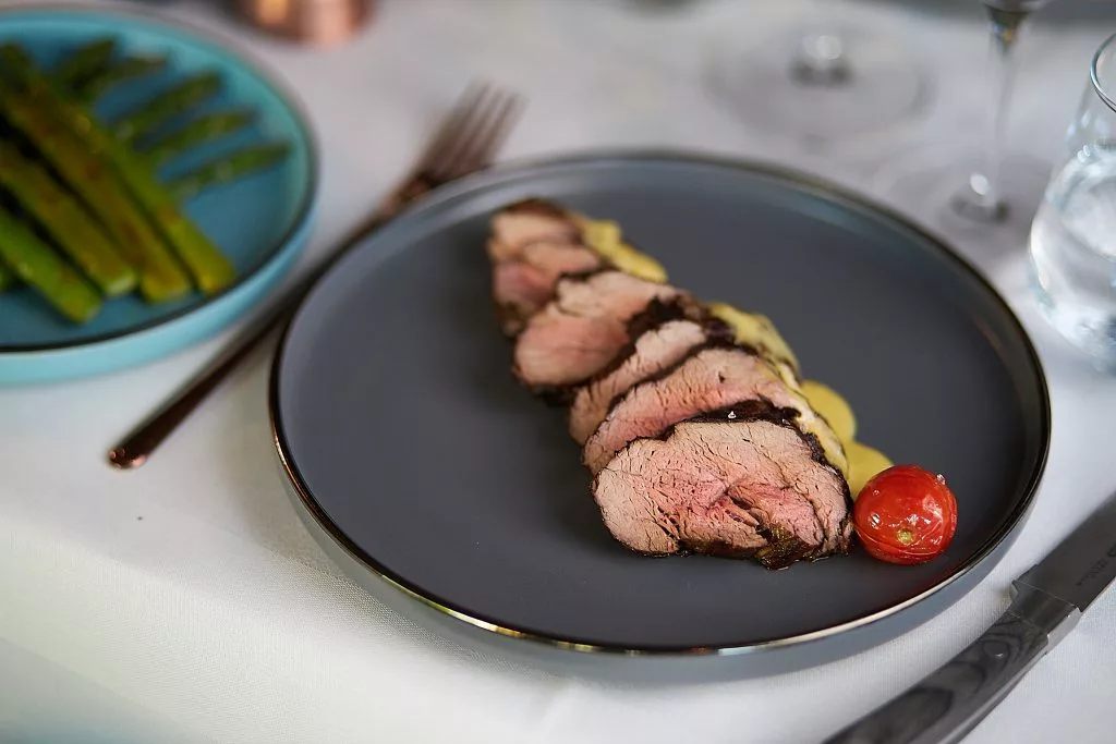 Mușchi de vită feliat cu roșie cherry, farfurie neagră — Restaurant Stejarii