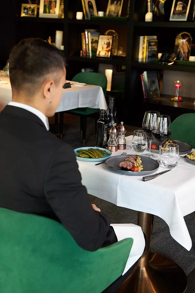 Client la masă în Restaurant Stejarii, cu biblioteca în fundal