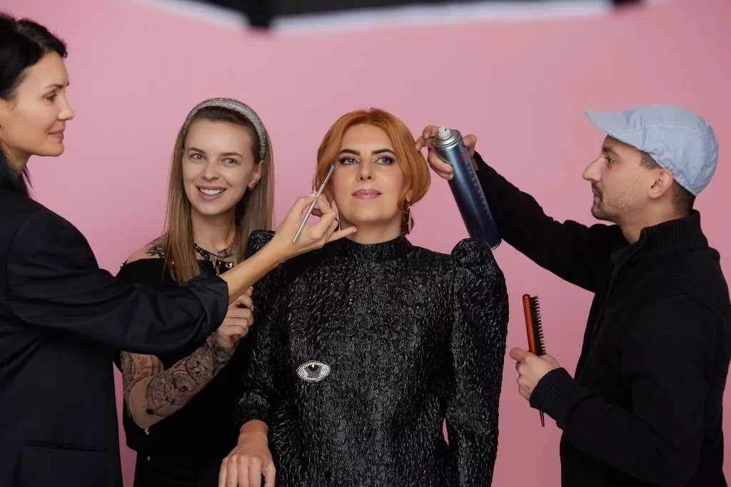 Echipa de hairstyling și machiaj lucrând cu Gina Bordaș pe platoul ședinței foto