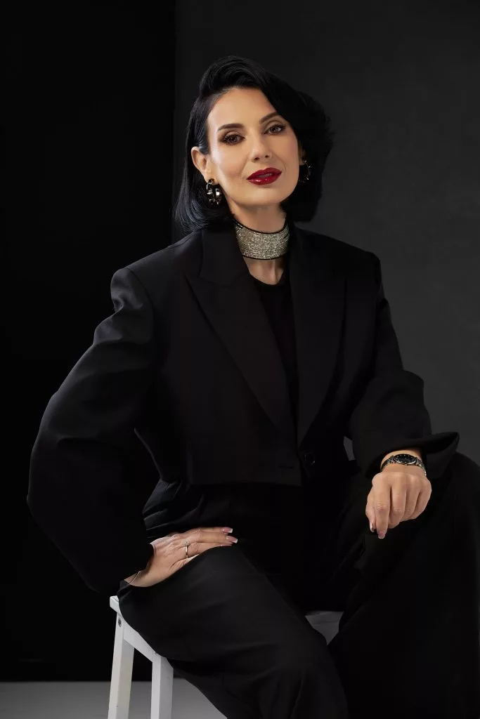 Amalia Păvălucă în sacou negru supradimensionat, portret pe fundal negru