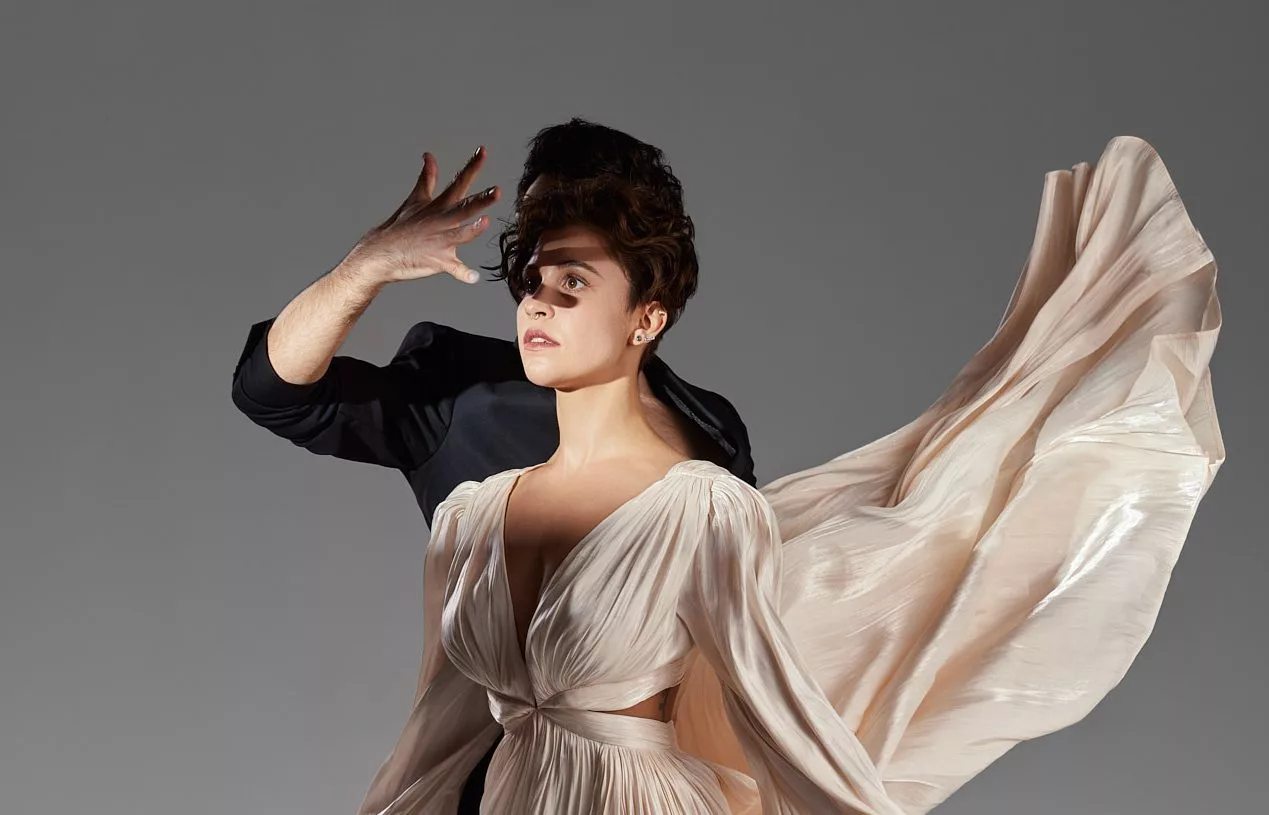 Model în rochie bej cu material fluturând, pe fundal gri — editorial Fashion Premium Magazine