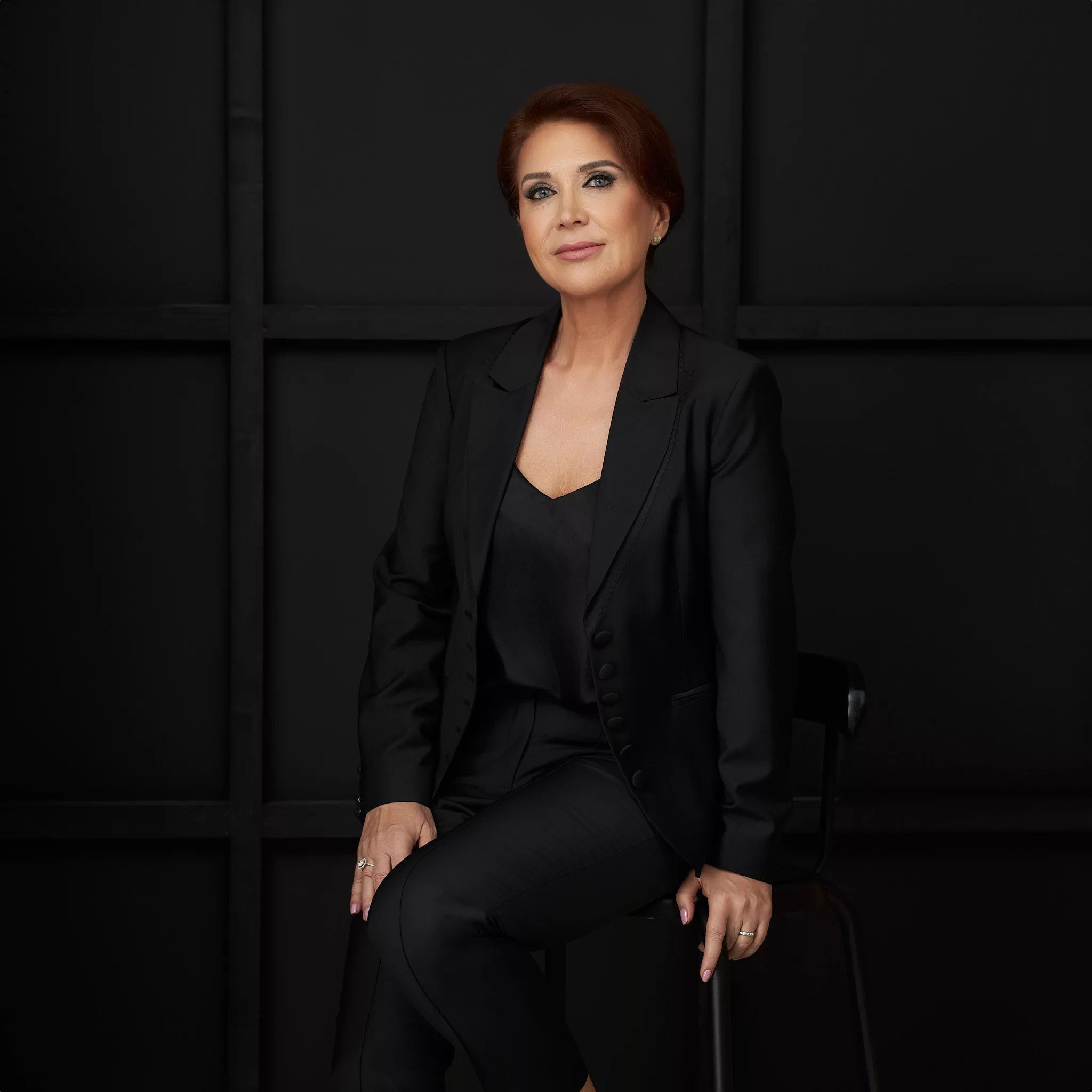 Nicoleta Radu în costum negru, portret pe fundal întunecat, fotografiat de Marius Tudose