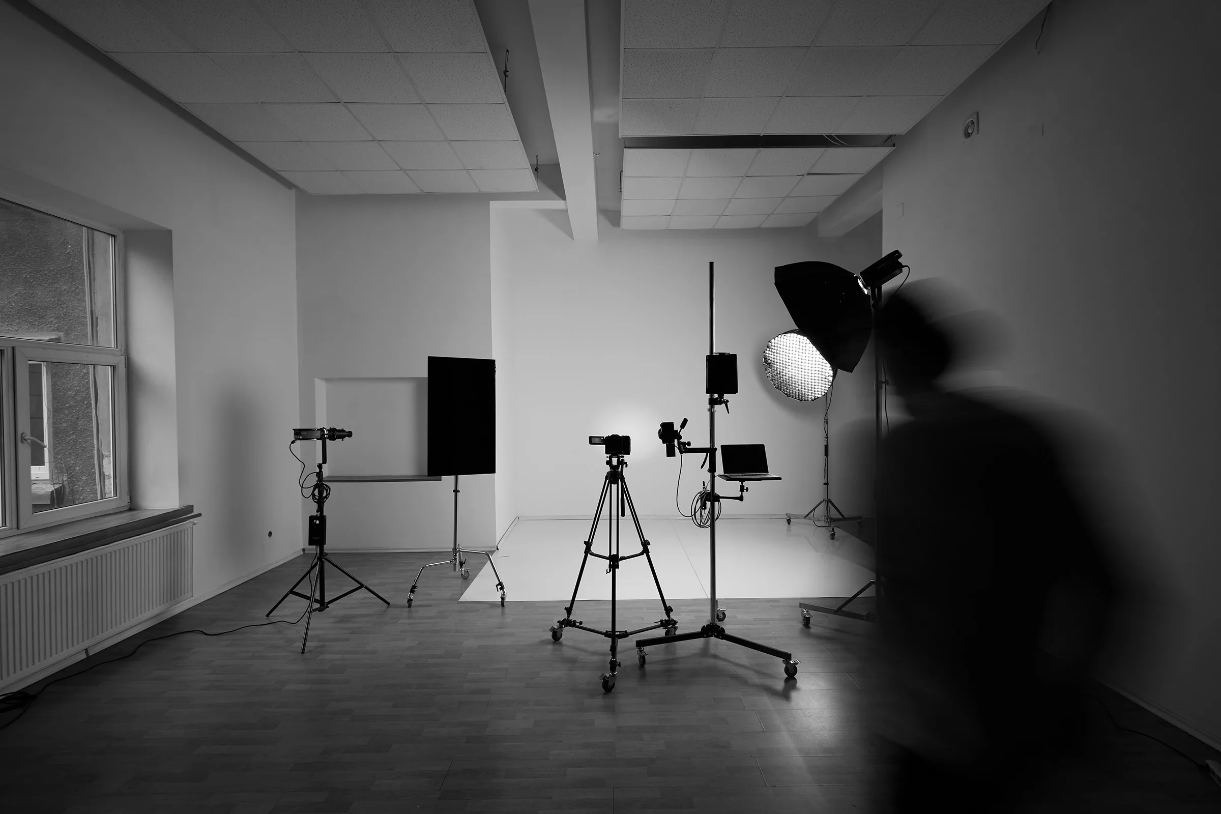 Studio foto gol, cu blițuri pe stative și o siluetă în mișcare — spațiul de lucru din București