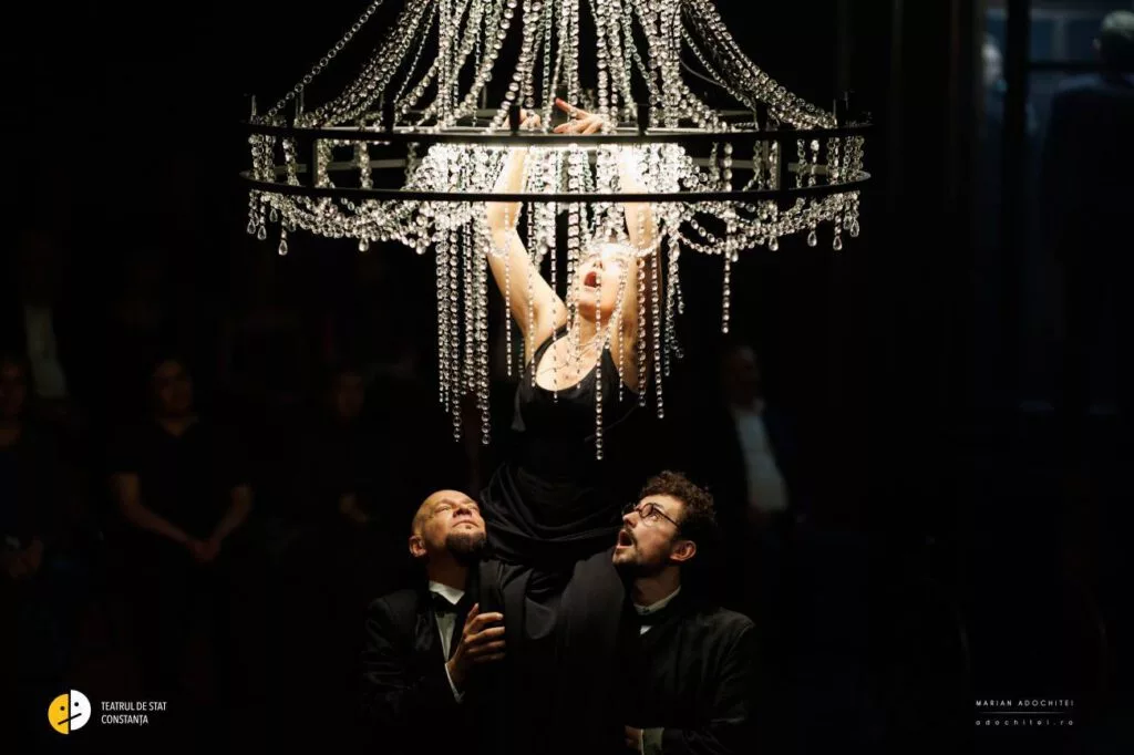 Actriță suspendată pe un candelabru, cu actori dedesubt — spectacol după Cehov