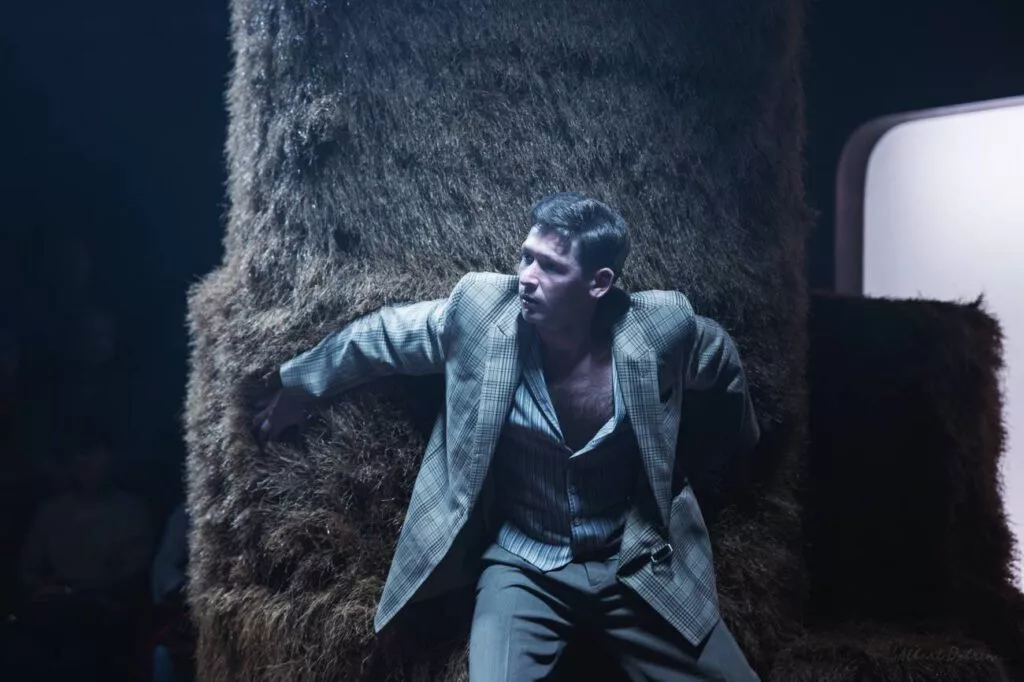 Actor sprijinit de un balot de fân, în lumină rece — spectacol după Cehov