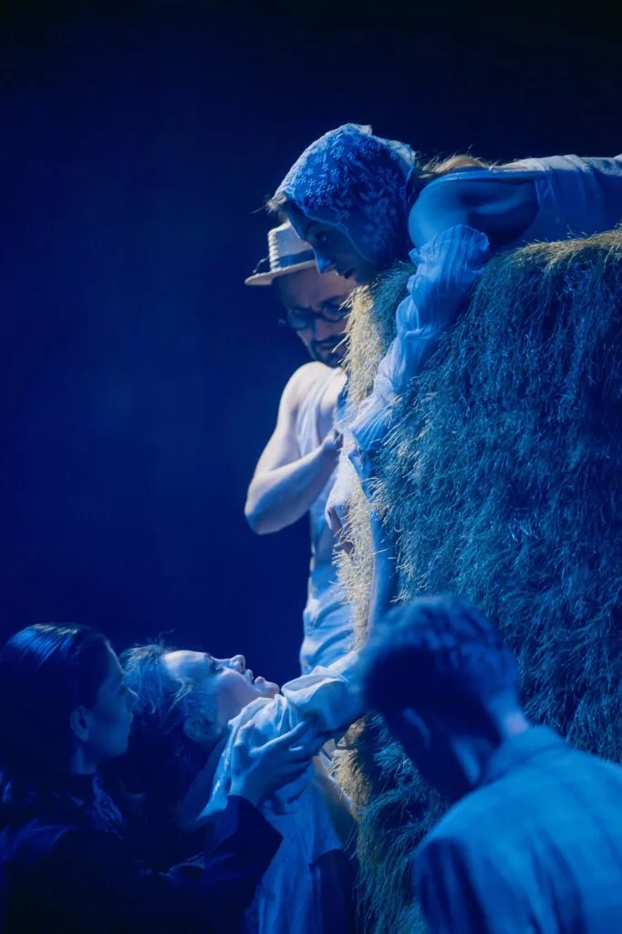Actori în lumină albastră, lângă un balot de fân — spectacol după Cehov